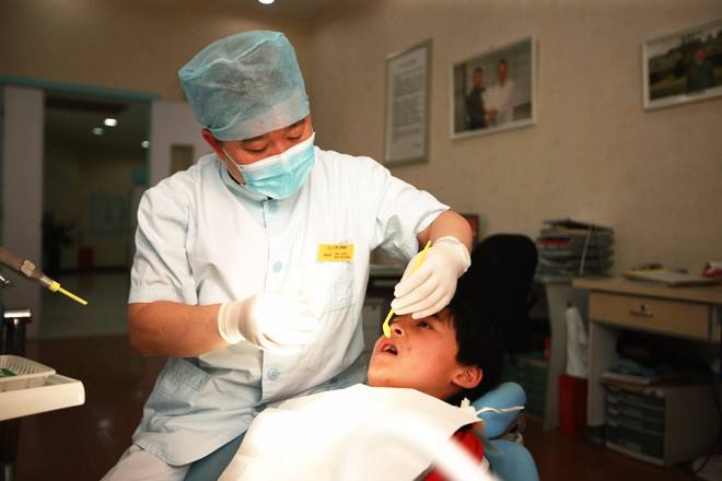 仁爱口腔科为农民工学生看牙-口腔科医生在给学生检查牙齿